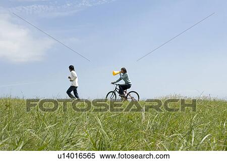 Young woman riding bicycle behind young men running View Large Photo Image Stock Photography - Young woman riding bicycle behind young men running. Fotosearch