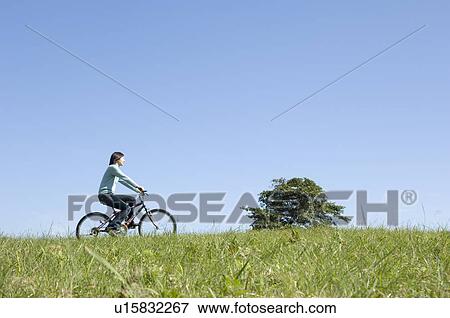 Stock Photo - Young woman riding bicycle. Fotosearch