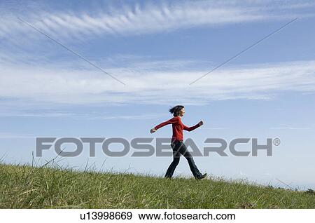 Young woman skipping in field View Large Photo Image Stock Photo - Young woman skipping in field. Fotosearch