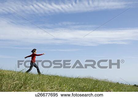 Stock Photography - Young woman skipping in field. Fotosearch