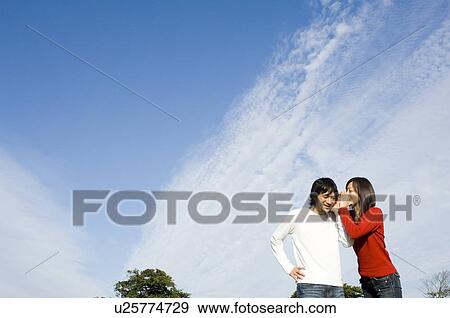 Young woman whispering to young man View Large Photo Image Stock Photo - Young woman whispering to young man. Fotosearch