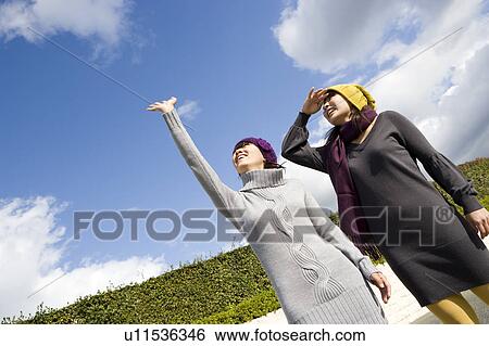 Two young women looking up View Large Photo Image Stock Photograph - Two young women looking up. Fotosearch