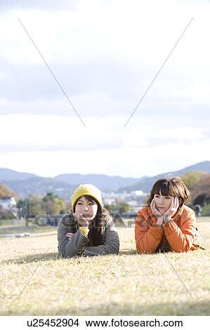 Two young women lying on lawn View Large Photo Image Picture - Two young women lying on lawn. Fotosearch