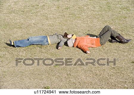 Two young women lying on lawn View Large Photo Image Stock Image - Two young women lying on lawn. Fotosearch