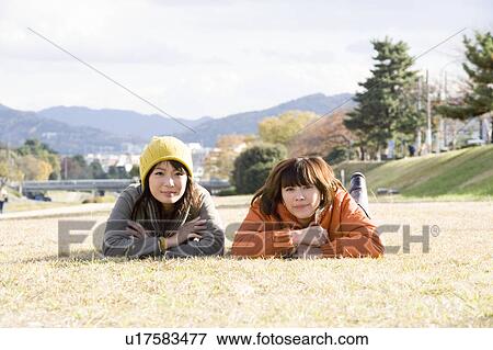 Stock Photo - Two young women lying on lawn. Fotosearch