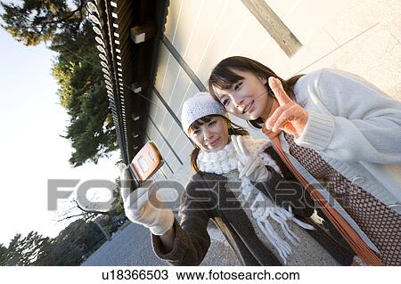 Two young women photographing themselves View Large Photo Image Stock Image - Two young women photographing themselves. Fotosearch