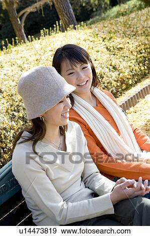 Two young women sitting on bench View Large Photo Image Stock Photo - Two young women sitting on bench. Fotosearch