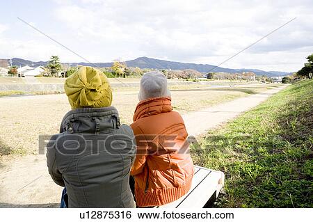 Two young women sitting on bench View Large Photo Image Stock Photograph - Two young women sitting on bench. Fotosearch