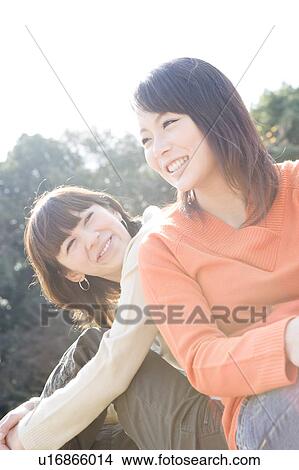Two young women sitting on lawn smiling View Large Photo Image Picture - Two young women sitting on lawn smiling. Fotosearch