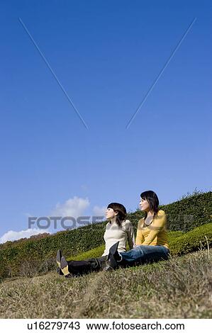 Two young women sitting on lawn View Large Photo Image Stock Image - Two young women sitting on lawn. Fotosearch
