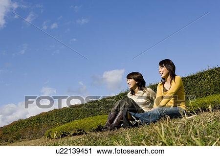 Two young women sitting on lawn View Large Photo Image Stock Image - Two young women sitting on lawn. Fotosearch
