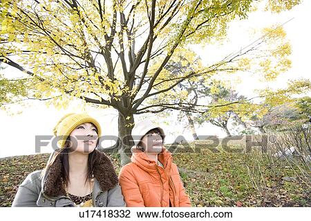 Two young women sitting on riverbank View Large Photo Image Stock Image - Two young women sitting on riverbank. Fotosearch