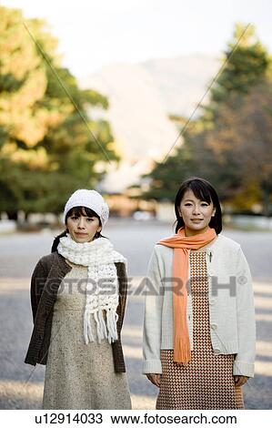 Stock Image - Two young women standing looking at camera. Fotosearch