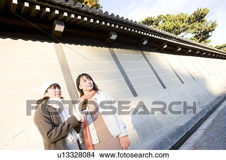 Two young women using mobile phone View Large Photo Image Picture - Two young women using mobile phone. Fotosearch