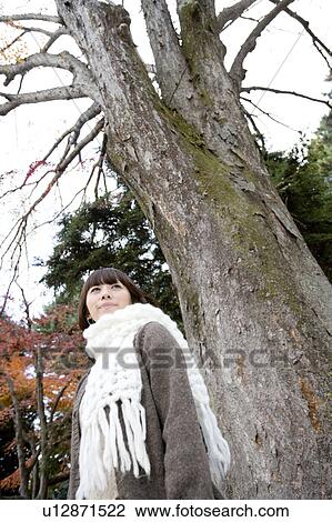 Young woman standing under tree View Large Photo Image Stock Image - Young woman standing under tree. Fotosearch