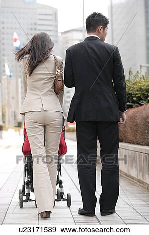 Business couple pushing baby stroller View Large Photo Image Stock Photo - Business couple pushing baby stroller. Fotosearch