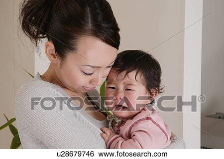 Mother holding crying baby View Large Photo Image Stock Photograph - Mother holding crying baby. Fotosearch