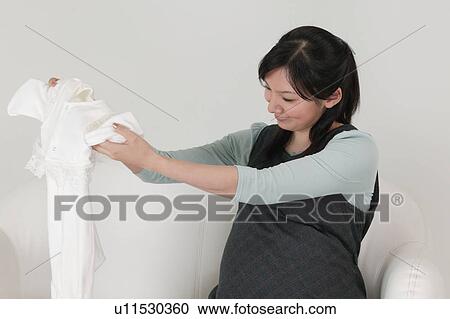 Pregnant woman holding baby clothes View Large Photo Image Stock Image - Pregnant woman holding baby clothes. Fotosearch