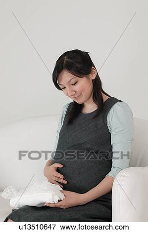 Pregnant woman holding baby clothes View Large Photo Image Stock Photo - Pregnant woman holding baby clothes. Fotosearch