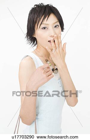 Stock Image - Young woman covering mouth with hand. Fotosearch
