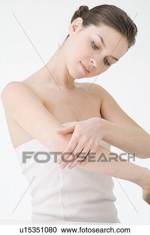 Young woman rubbing lotion on arm View Large Photo Image Stock Image - Young woman rubbing lotion on arm. Fotosearch
