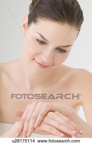 Young woman rubbing lotion on hands View Large Photo Image Picture - Young woman rubbing lotion on hands. Fotosearch