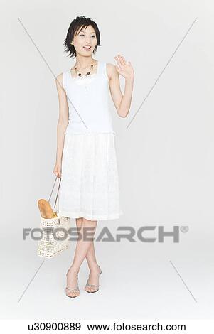 Stock Photo - Young woman standing and waving. Fotosearch