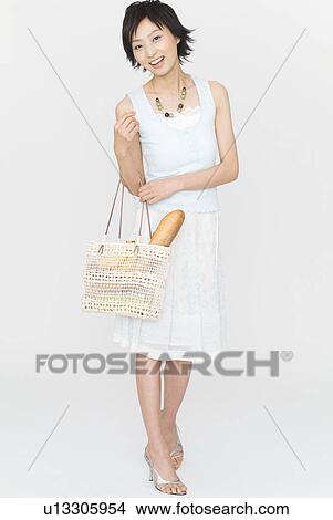 Picture - Young woman standing with bag. Fotosearch