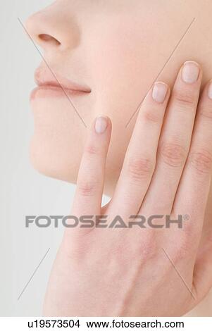 Young woman touching her cheek, close-up View Large Photo Image Picture - Young woman touching her cheek, close-up. Fotosearch