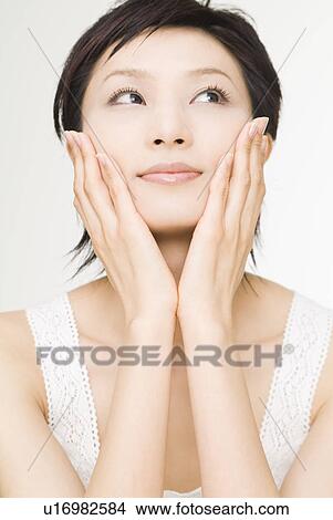 Young woman touching her cheeks View Large Photo Image Picture - Young woman touching her cheeks. Fotosearch