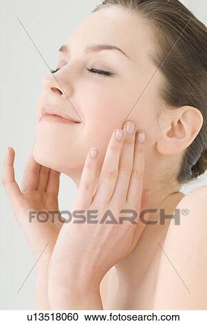 Stock Image - Young woman touching her cheeks. Fotosearch