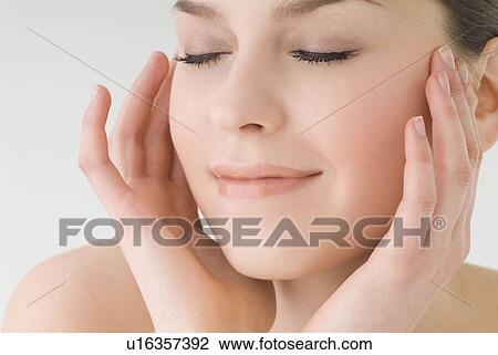 Young woman touching her cheeks View Large Photo Image Stock Image - Young woman touching her cheeks. Fotosearch