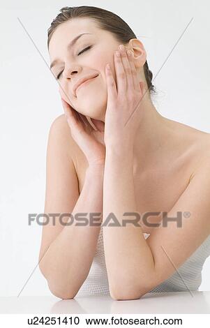 Young woman touching her cheeks View Large Photo Image Stock Image - Young woman touching her cheeks. Fotosearch