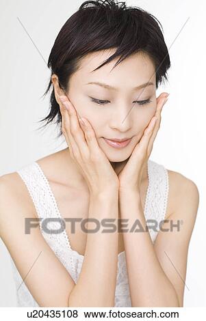 Young woman touching her cheeks View Large Photo Image Stock Photo - Young woman touching her cheeks. Fotosearch