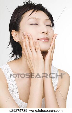 Young woman touching her cheeks View Large Photo Image Stock Photo - Young woman touching her cheeks. Fotosearch