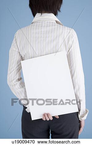 Businesswoman holding blank placard behind her View Large Photo Image Stock Image - Businesswoman holding blank placard behind her. Fotosearch