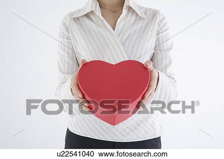 Stock Image - Businesswoman holding heart-shaped box. Fotosearch