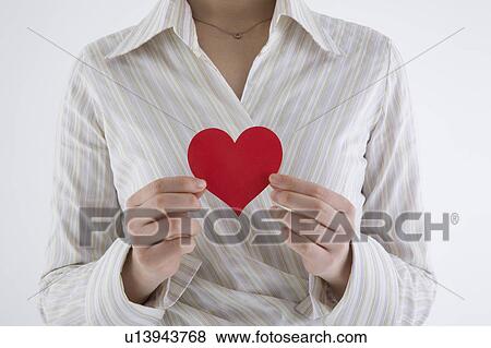 Stock Photo - Businesswoman holding heart-shaped paper. Fotosearch