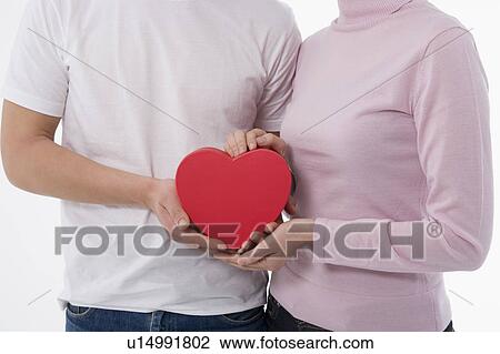Man and woman holding heart-shaped box View Large Photo Image Stock Image - Man and woman holding heart-shaped box. Fotosearch