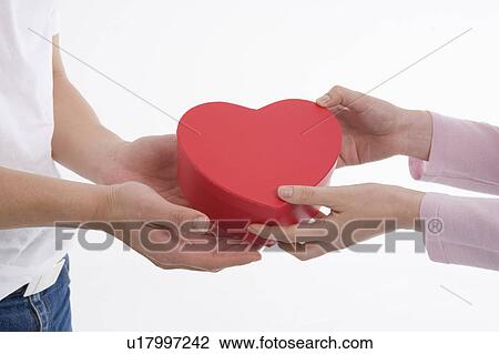 Woman giving man heart-shaped box View Large Photo Image Stock Image - Woman giving man heart-shaped box. Fotosearch