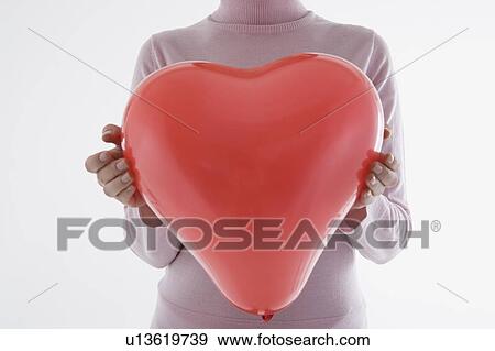 Woman holding heart-shaped balloon View Large Photo Image Stock Photo - Woman holding heart-shaped balloon. Fotosearch