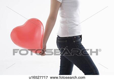 Woman holding heart-shaped balloon View Large Photo Image Stock Photo - Woman holding heart-shaped balloon. Fotosearch