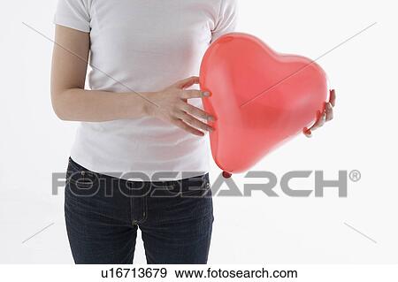 Woman holding heart-shaped balloon View Large Photo Image Stock Photo - Woman holding heart-shaped balloon. Fotosearch
