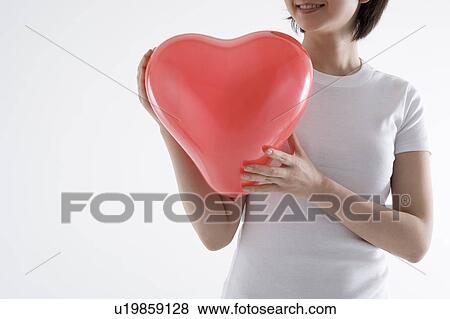 Woman holding heart-shaped balloon View Large Photo Image Stock Photo - Woman holding heart-shaped balloon. Fotosearch