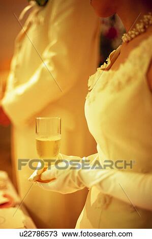Bride and groom holding a glass of champagne View Large Photo Image Stock Image - Bride and groom holding a glass of champagne. Fotosearch