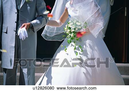 Stock Image - Midsection of bride and groom. Fotosearch