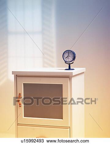 Stock Image - A small circular clock on a white cabinet. Fotosearch