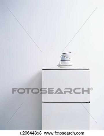 Stock Photo - A stack of cups and saucers on refrigerator. Fotosearch