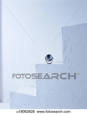 Stock Photo - A tiny globe kept on stairs. Fotosearch