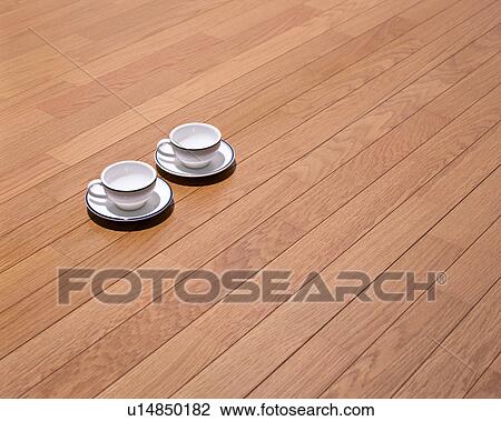 Stock Image - Two cups and saucers on hardwood floor. Fotosearch
